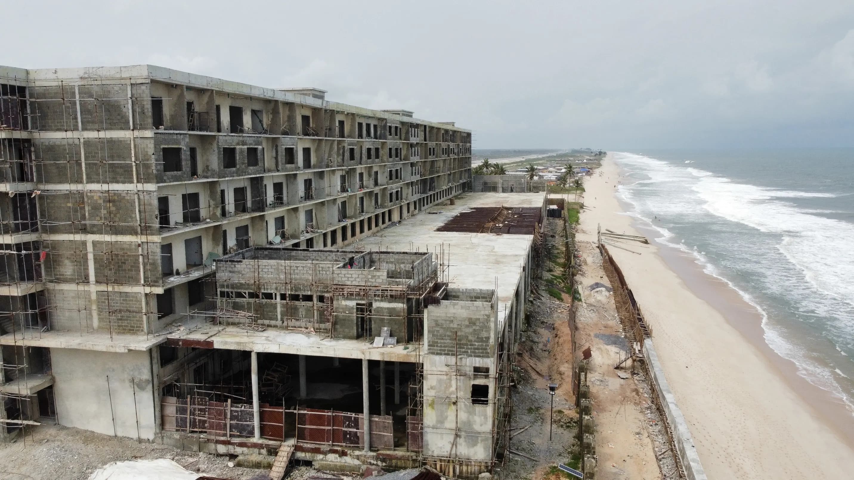Aerial photograph of NJS Beach Resort under construction, showing the multi-storey block, site works and the adjacent coastline.